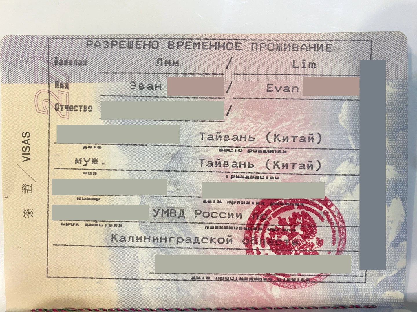 An image of a Temporary Residence Permit stamp in a passport, redacted for privacy